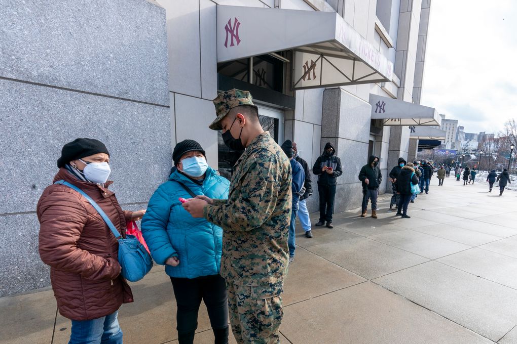 FILE – In this Feb. 5, 2021, file photo, a National Guardsman helps people standing in line to register for an appointment for their first dose of the COVID-19 vaccine at a vaccination site at Yankee Stadium in the Bronx borough of New York. More than 1 million COVID-19 vaccination shots have been given at Major League Baseball stadiums, with the Oakland Coliseum and Marlins Park among the sites planning to continue operating after opening day. The 11 ballparks that converted to mass vaccination centers in the offseason combined to pass a million total shots this week, MLB said Friday, March 26. (AP Photo/Mary Altaffer, File)