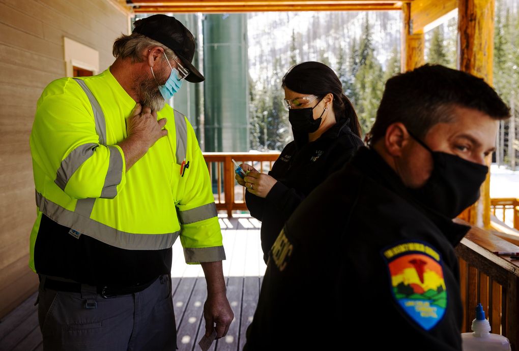 Lake Chelan Health paramedic Mistaya Johnston, center, prepares to administer the Moderna COVID-19 vaccine to John Widell, left, who works at the water treatment plant operated by Rio Tinto in the North Cascades, on March 30.  (Amanda Snyder / The Seattle Times)