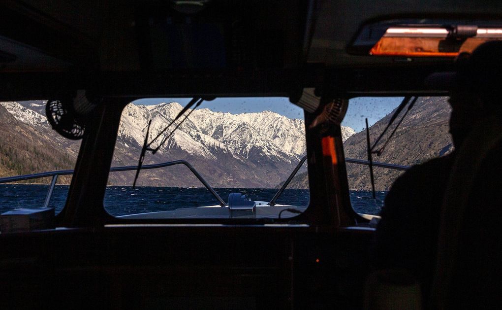 Mountains of the North Cascades loom in the distance as Ray Eickmeyer and Mistaya Johnston travel by boat on March 30 to vaccinate those at Holden Village, Stehekin and workers at a mine remediation water treatment plant operated by Rio Tinto. (Amanda Snyder / The Seattle Times)