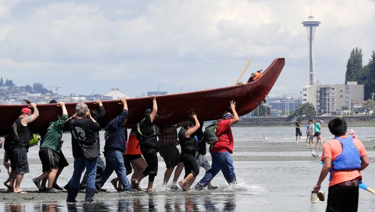 Tribal canoe being carried by 20 Tribal citizens