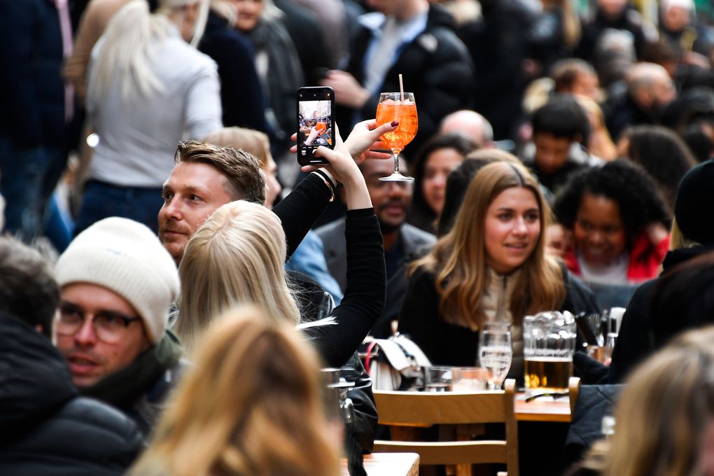 A woman takes a phone picture of her drink in Soho, London, on the day some of England’s coronavirus lockdown restrictions were eased by the British government, Monday, April 12, 2021. People across England can get their hair cut, eat and drink outside at restaurants and browse for clothes, books and other “non-essential” items as shops and gyms reopened Monday after months of lockdown. (AP Photo/Alberto Pezzali)