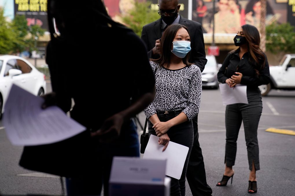 People wait in line, resumes in hand, while waiting to apply for jobs during an outdoor hiring event for the Circa resort and casino, Tuesday, April 27, 2021, in Las Vegas. The casino was looking to hire around a hundred hospitality workers. (AP Photo/John Locher)