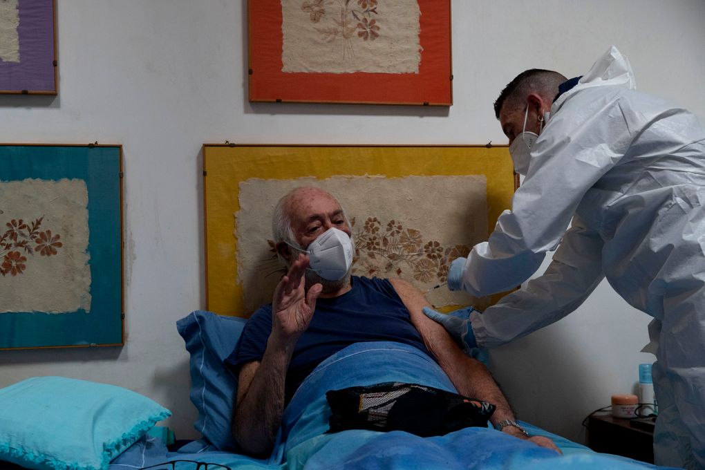 Nurse Luigi Lauri administers a dose of the Pfizer vaccine to 85-year old Giorgio Tagliacarne at his home in Rome, Tuesday, April 27, 2021. The doctor and nurse manage just 12 shots day _ six in the morning, six in the afternoon _ making house calls to Rome’s homebound elderly to administer coronavirus vaccines and along with them, the hope that Italy’s most fragile might soon emerge from the pandemic. (AP Photo/Alessandra Tarantino)