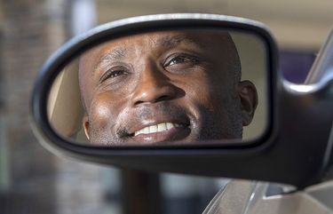 Raymond Evans, who delivers for Door Dash, is reflected in the side mirror of his car in a Renton shopping center next to restaurants where he occasionally picks up food for customers Friday, May 14, 2021.217145