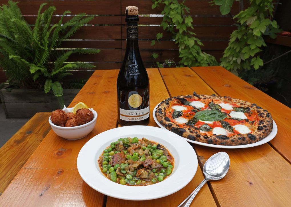 Clockwise from foreground: the la vignarola stew, the baccala fritters and Margherita pizza seen on the patio of Bar del Corso on Beacon Hill. (Ken Lambert / The Seattle Times)
