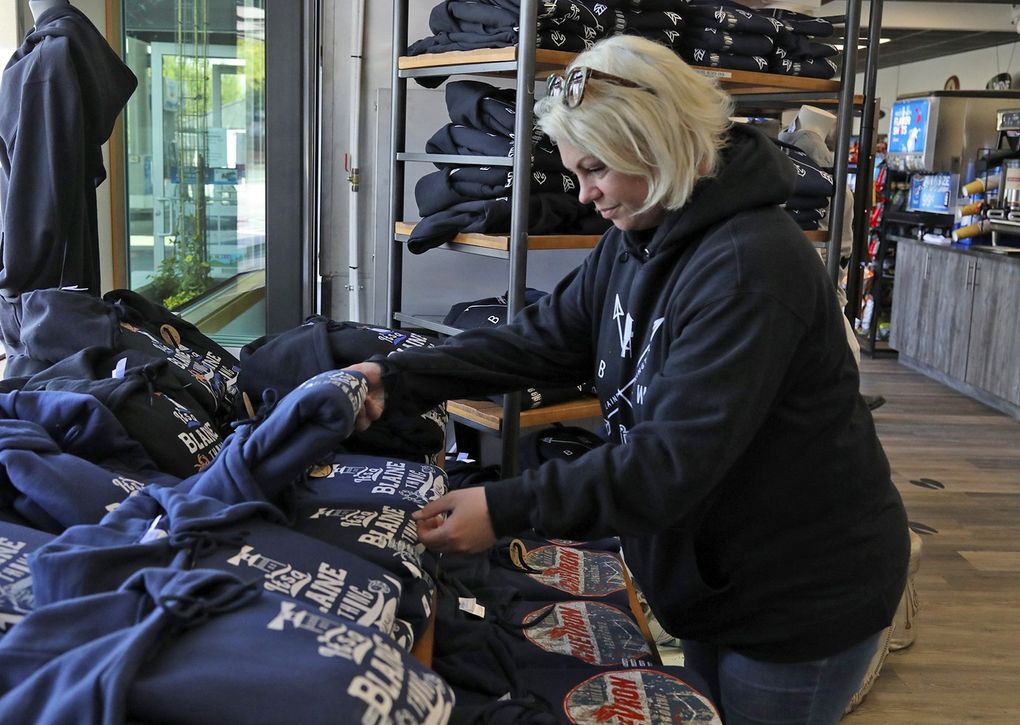 Skye Hill, co-owner of the Chevron service station on Peace Portal Drive in Blaine, arranges hoodies for sale. When the fuel sales plummeted, the business expanded its convenience store inventory. (Greg Gilbert / The Seattle Times)