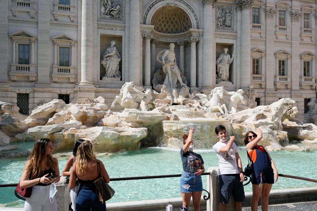 FILE – In this Friday, June 4, 2021 file photo, tourists throw their coins into the Trevi fountain as a wish to come back to the eternal city, in downtown Rome. The European Union is recommending that member countries start lifting restrictions on tourists from the United States. EU members agreed Wednesday, June 16, 2021 to add the U.S. to the list of countries in whose cases restrictions on non-essential travel should be lifted. (AP Photo/Gregorio Borgia, File)