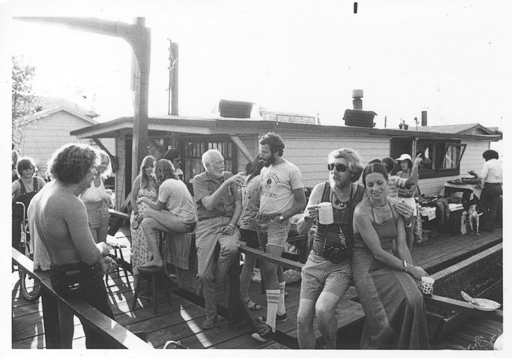 Before they turned into pricey residences, Lake Union houseboats were cheap rentals for UW artist/intellectual types in the 1960s and ’70s. This photo was taken at a luau in the early 1970s at the dock where Jann McFarland, now 79, has had a houseboat since 1973. “Party lasted two days, cooked a pig in the ground, live music, dancing, smoking dope – the usual,” she says. The white-haired man sitting on a railing in the middle of the photo is Terry Pettus, who worked for various newspapers around the state and organized what is today’s Floating Homes Association. (Jann McFarland)