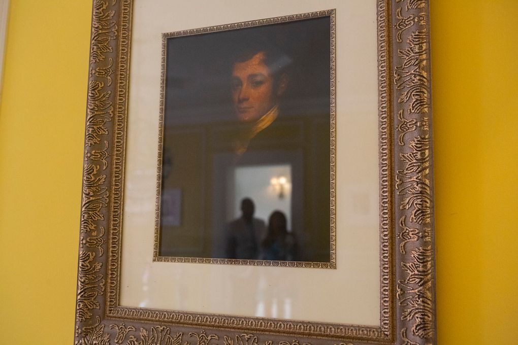 Jamie and Frantz Arty are reflected in a portrait of the original homeowner, William Townsend McCoun, a prominent New York abolitionist and judge, who lived in the mansion until his death in 1878. (Calla Kessler for The Washington Post)