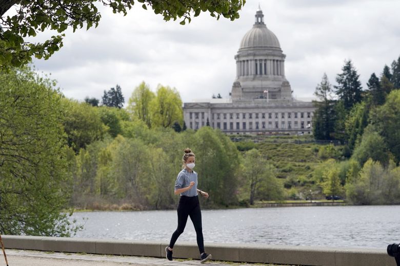A person wears a mask while jogging April 27 near the Capitol in Olympia. (Ted S. Warren / AP)