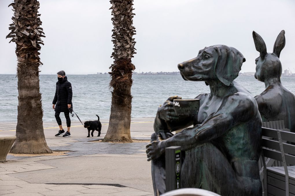 A person walks a dog along St. Kilda foreshore in Melbourne, Monday, Aug. 16, 2021. Melbourne reported 22 new infections on while the state Premier Danial Andrews said Australia’ largest city after Sydney was at a “tipping point” in its battle to stamp out all infections. (Daniel Pockett/AAP Image via AP)