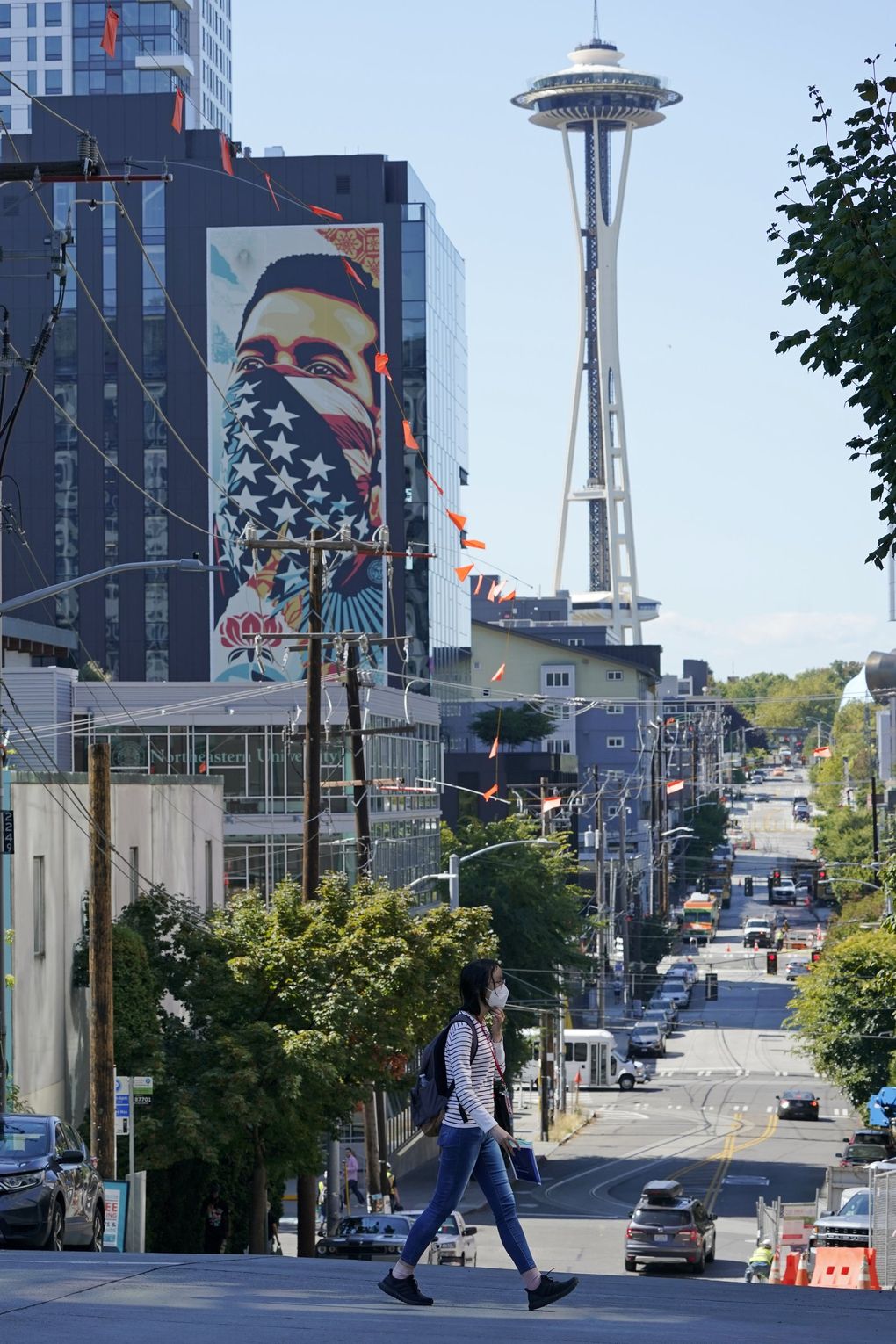 A pedestrian wears a mask while crossing a street near the Space Needle in Seattle.