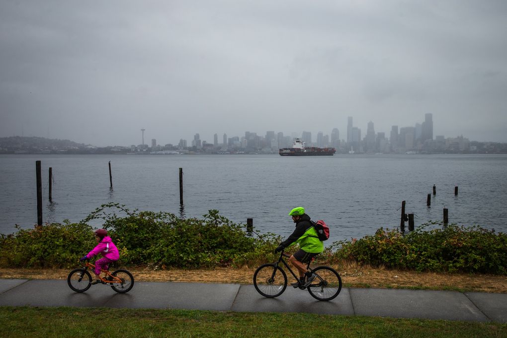Cyclists brave a light rain for a gray skyline view along Harbor Avenue in West Seattle.