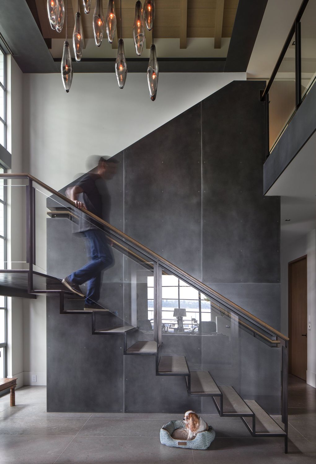 The dramatic floating staircase of this Washington Park home  rises in the grand entry hall, with French limestone floors and a textured steel wall crafted by Decorative Metal Arts. “The challenge to design the stairs was to keep them as open as possible through the window,” says project manager Michael McFadden of Stuart Silk Architects. (Steve Ringman / The Seattle Times, 2017)