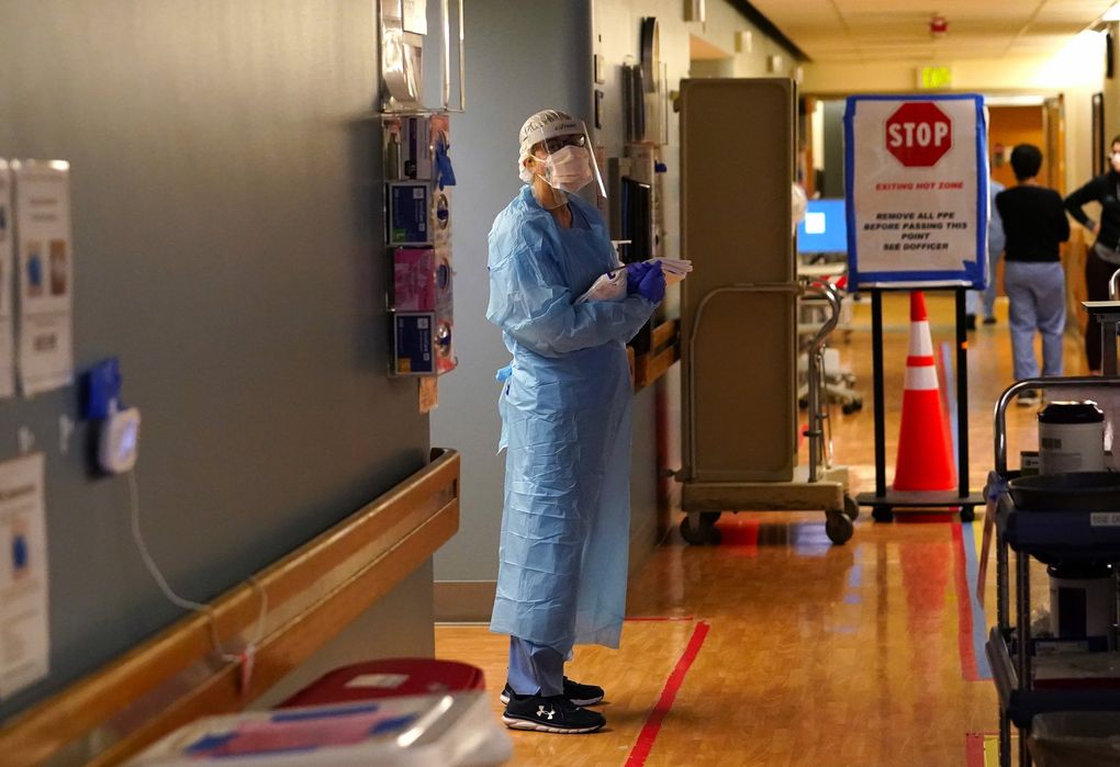 A registered nurse stands in the “hot zone,” defined by red tape on the floor, as she waits to exchange equipment with a colleague who will remain on the other side.
