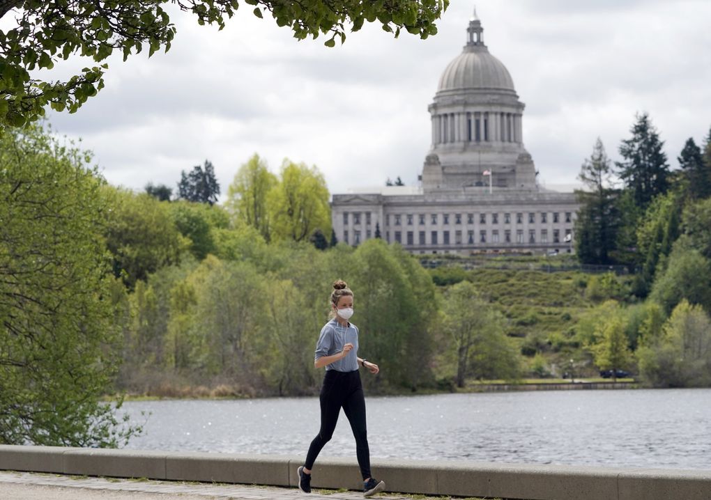 A person wears a mask while jogging near the Capitol in Olympia.