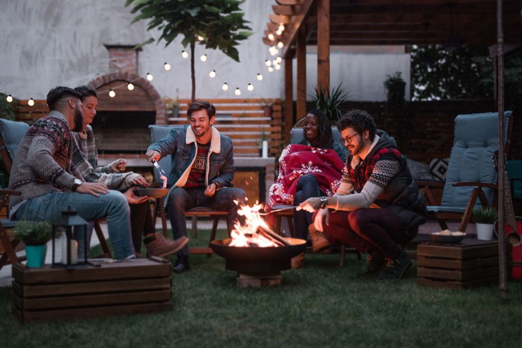 Adding fluffy cushions and blankets around a fire pit is a quick way to increase cozy comfort outside as the weather cools. A covered pergola and string lights are additional ways to activate your outdoor space well into winter, says Seattle landscape designer Lisa Port. (Getty Images)