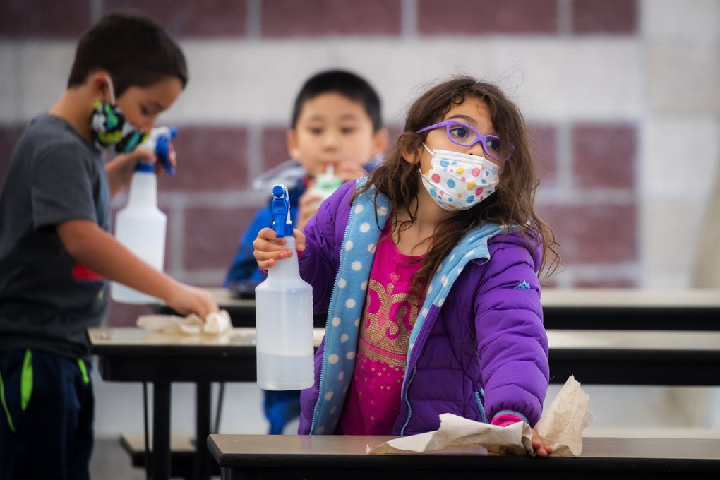 A second-grader wipes down her lunch area with sanitizing spray.