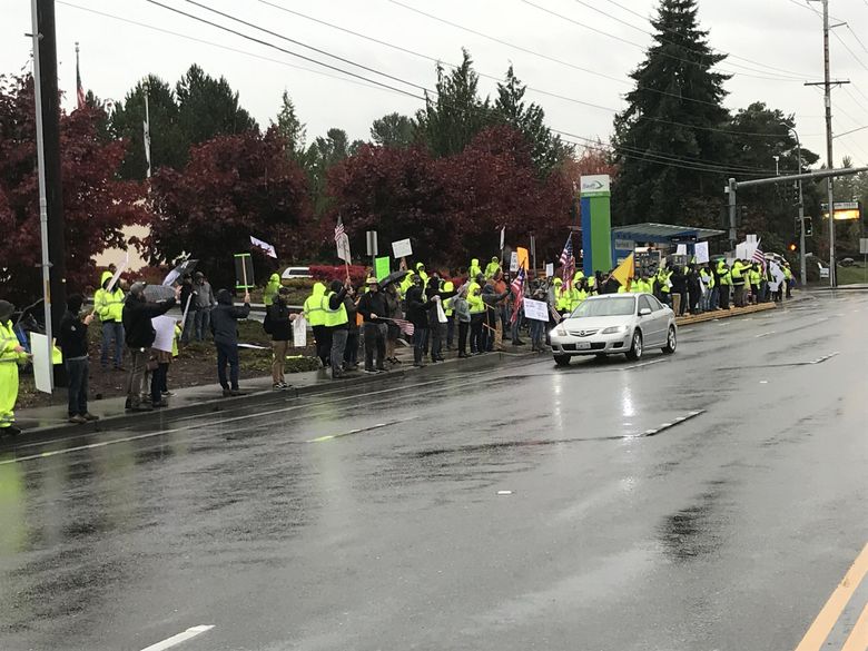 Boeing workers protesting the company’s vaccine requirement wave signs at passing cars Friday outside Boeing’s production plant in Everett. (Dominic Gates / The Seattle Times)