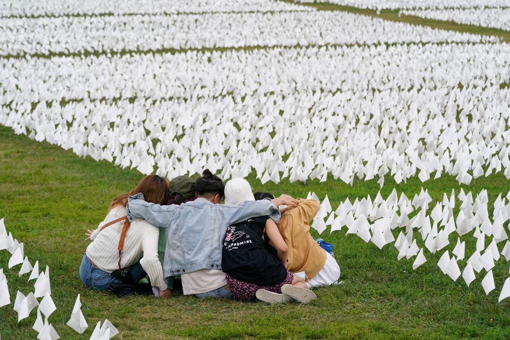 FILE – In this Sept. 21, 2021, file photo, visitors sit among white flags that are part of artist Suzanne Brennan Firstenberg’s “In America: Remember,” a temporary art installation to commemorate Americans who have died of COVID-19, on the National Mall in Washington. Firstenberg was struck by how strangers connected in their grief at the installation, which ended Oct. 3. (AP Photo/Patrick Semansky, File)