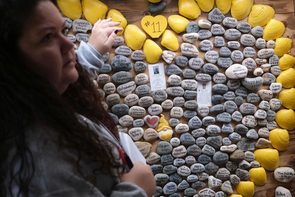 Rima Samman looks for certain names of people who died from coronavirus at Rami’s Heart COVID-19 Memorial in Wall Township, N.J., Wednesday, Oct. 27, 2021. The memorial, which started out on a jersey shore beach made of shells and rocks, has found a permanent home at Allaire Community Farm. Started by Rima Samman and named after her brother Rami, who was killed by the coronavirus, it has grown to more than 4,000 victims’ names, with dozens of new names added every week. (AP Photo/Seth Wenig)