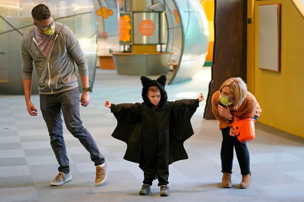 Grayson Martin, 3, poses in his costume as his parents Rachelle and Patrick Martin, look on, during a visit to Discovery Gateway Children’s Museum on Thursday, Oct. 28, 2021, in Salt Lake City. Coronavirus cases in the U.S. are on the decline, and trick-or-treaters can feel safer collecting candy. (AP Photo/Rick Bowmer)