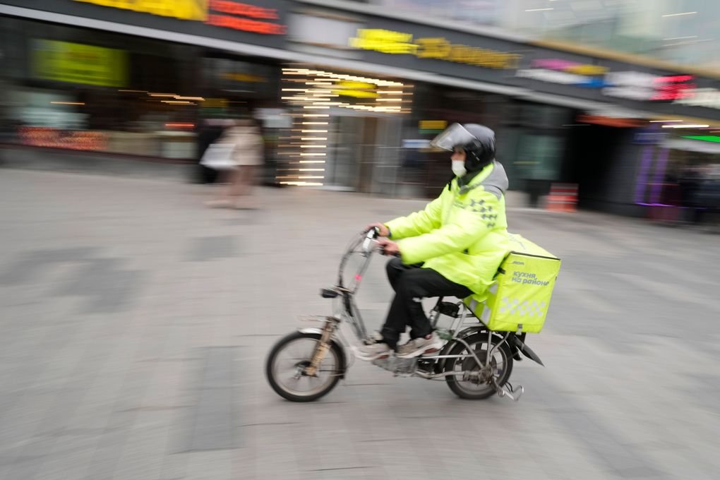 A food delivery courier rides a bicycle in Moscow, Russia, Friday, Oct. 29, 2021. Russia has recorded another record of daily coronavirus deaths even as authorities hope to stem contagion by keeping most people off work. Moscow introduced the measure starting from Thursday, shutting kindergartens, schools, gyms, entertainment venues and most stores, and restricting restaurants and cafes to only takeout or delivery. (AP Photo/Pavel Golovkin)