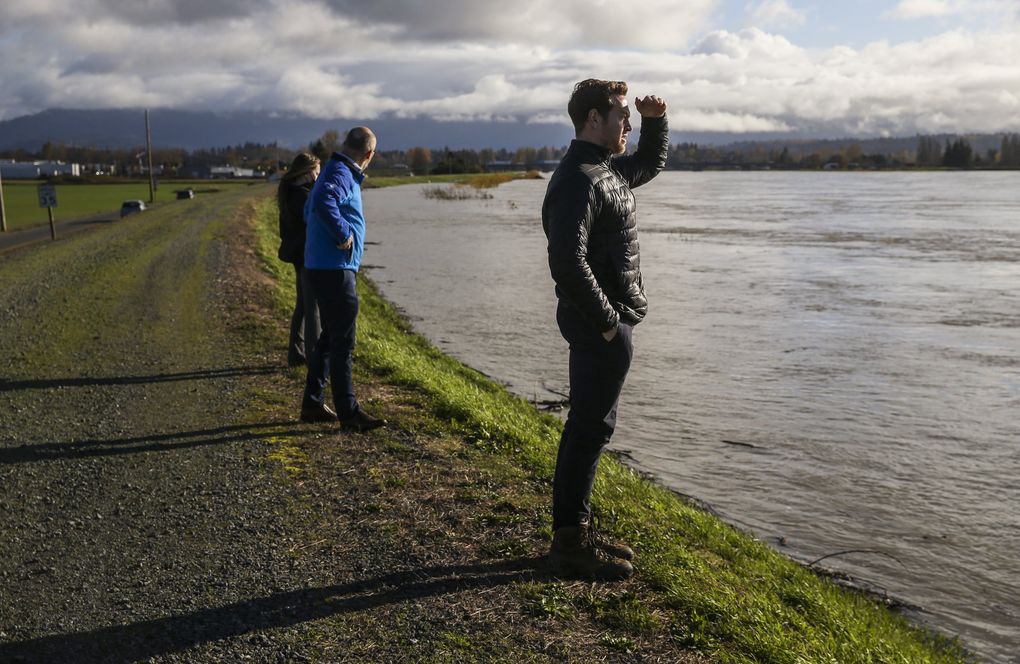 Tyler Steinman, owner of the Foothills Toyota car dealership, right, checks out the rising Skagit River as it flooded areas in western Mount Vernon on Tuesday.  Steinman said his dealership had moved all its cars to safer ground in case of flooding.  (Amanda Snyder / The Seattle Times)