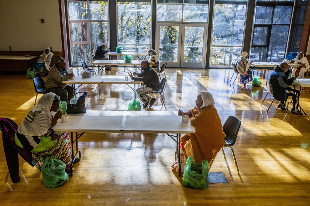 Anggota komunitas Afrika Timur berkumpul untuk makan di Pusat Komunitas Northgate.  Program ini menawarkan makanan yang akrab secara budaya dan bergizi.  (Daniel Kim / The Seattle Times)
