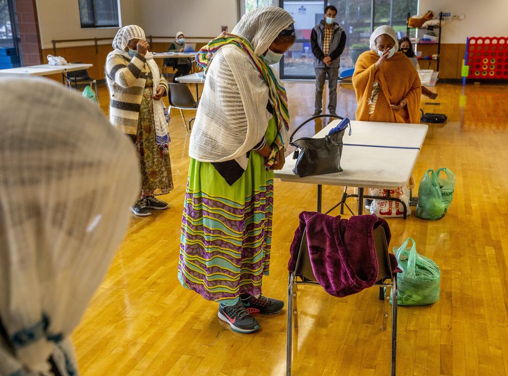 Alefech Berhe, center, prays with other East African community members before receiving their main course at Northgate Community Center. (Daniel Kim / The Seattle Times)