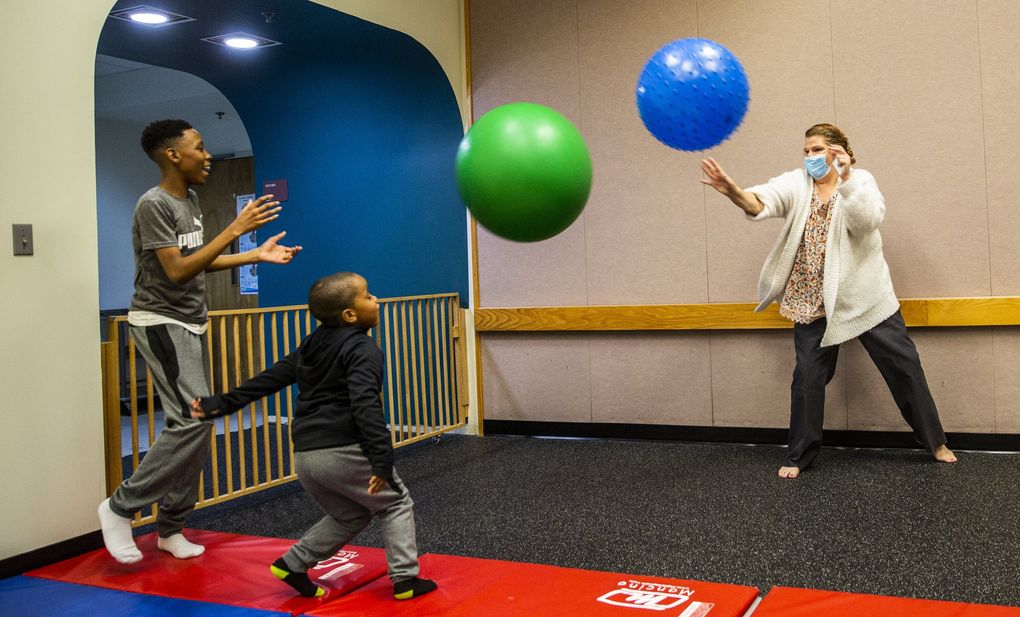 WISe (Wraparound with Intensive Services) parent partner Barbie Jo Wagner, right, plays with Samari, center, and Josiah at Childhaven in Auburn. (Daniel Kim / The Seattle Times)