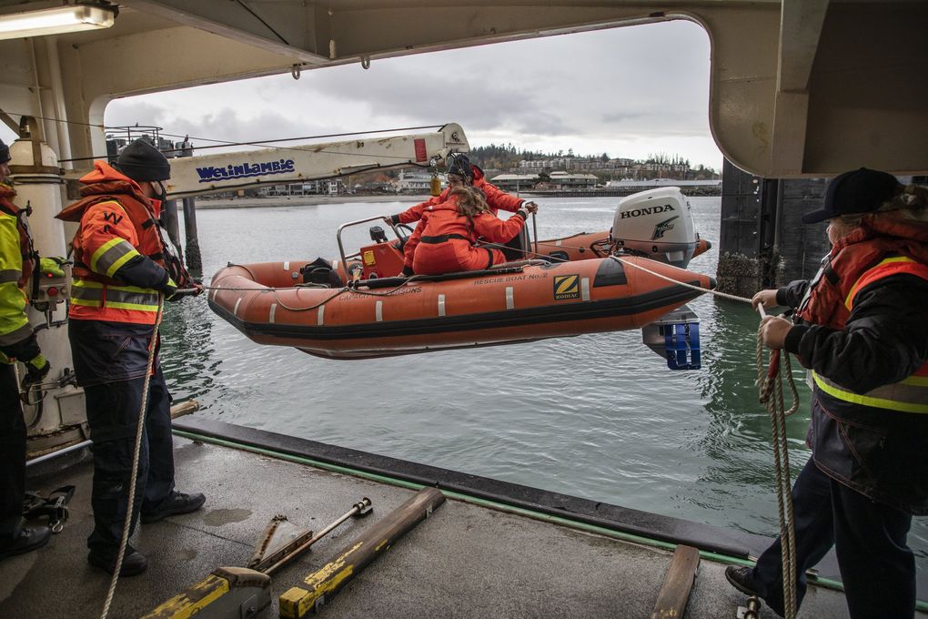Crew members practice launching a rescue boat before the Kaleetan takes on cars in Edmonds. Coast Guard rules require a certain quota of safety-trained staff, or the ferry can’t sail. (Steve Ringman / The Seattle Times)